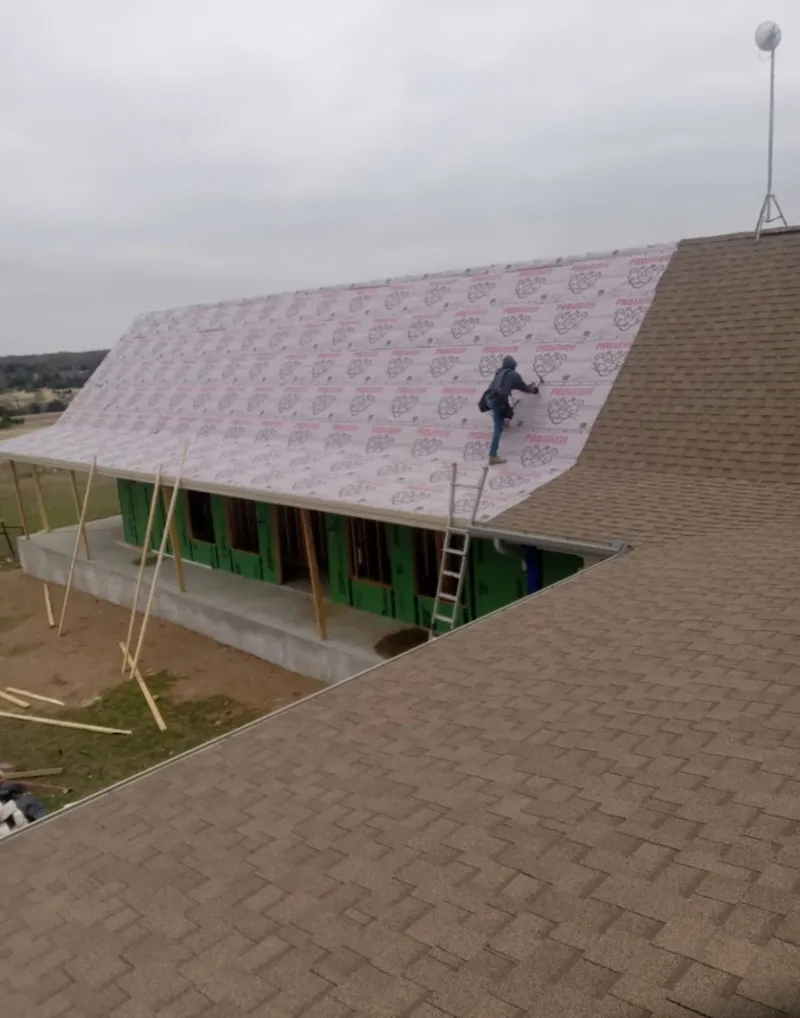 Worker preparing underlayment for a metal roof installation in Matteson